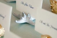 gold and silver sea creature figurines holding escort cards are very chic and timeless for a beach wedding