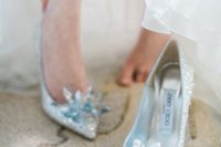 super shiny silver wedding shoes fully covered with rhinestones and with oversized blue rhinestone flowers are a very glam solution