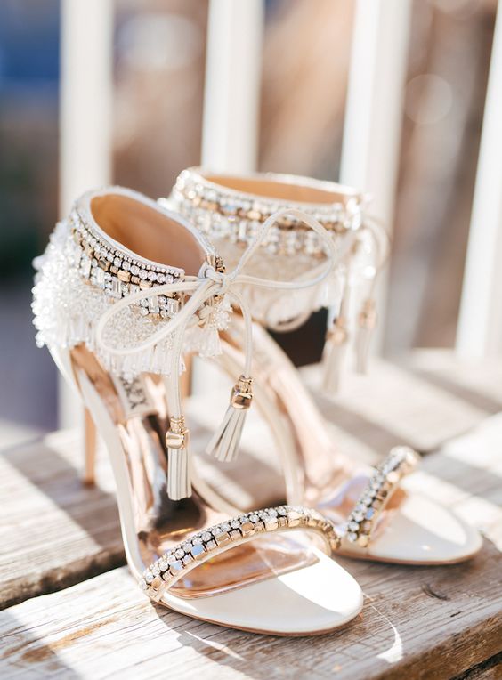 white heavily embellished wedding shoes with thin straps and heavy embellishments on the backs plus tassels