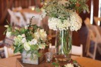 a barn wedding centerpiece of candles, neutral blooms and greenery plus succulents and a wooden box