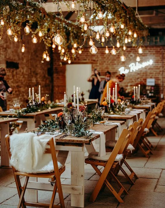 a barn wedding venue decorated with bulbs, greenery and candles on the tables is a lovely and welcoming space to enjoy