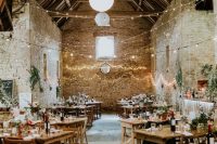 a barn wedding venue decorated with string lights, paper pendant lamps and candles on the tables is a cool way to refresh the space