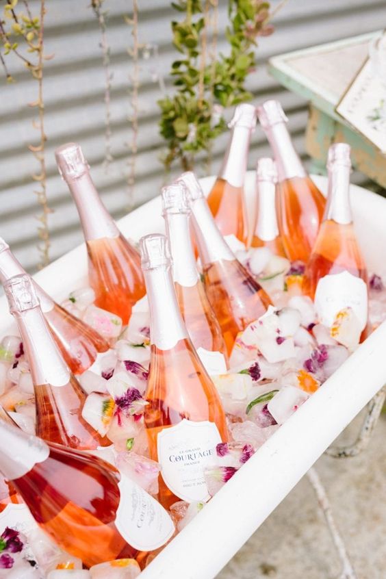 a bathtub with flower ice and prosecco is a lovely way to store drinks for an outdoor shower and keep them cold at the same time