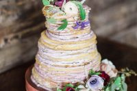 a beautiful crepe wedding cake with lavender cream, white, lilac, burgundy blooms and greenery and fruit slices is chic