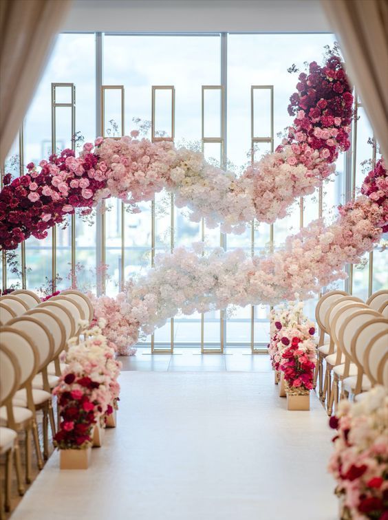 a beautiful wedding ceremony space done with ombre floral garlands, with matching floral arrangements that line up the aisle