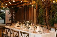 a beautiful wedding venue with greenery and string lights and pillar candles on the table is a cool and welcoming space