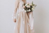 a blush A-line wedding dress with a v-neckline, puff sheer sleeves and white floral appliques for a spring bride