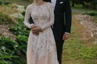 a blush A-line wedding dress with white lace with long sleeves, a high neckline and a train is very romantic