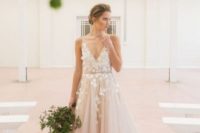 a blush tulle wedding dress with floral appliques on the bodice and a deep V-neckline for a modern princess-style bride