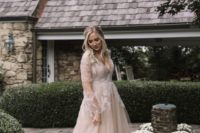 a blush wedding dress with a deep V-neckline, illusion sleeves and white lace appliques for a romantic bride