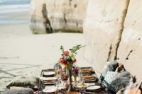 a boho beach bridal shower picnic with bold printed and fur pillows, bright blooms and delicious food