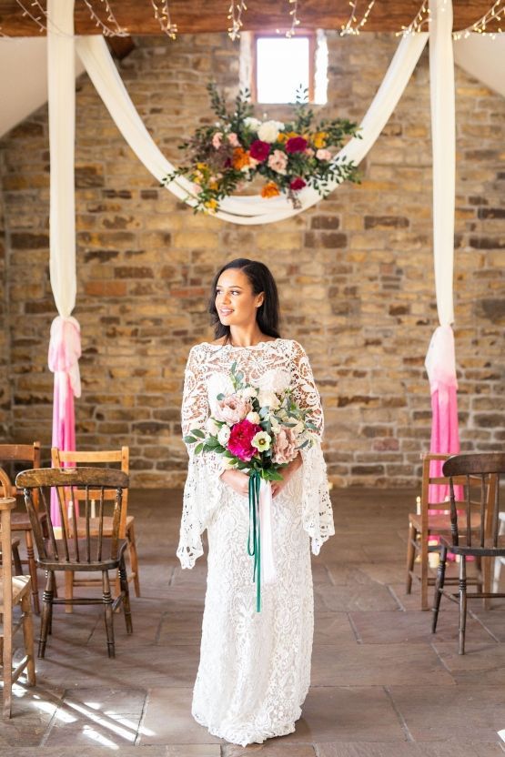 a boho lace fitting wedding dress with a high illusion neckline, bell sleeves for a modern boho barn bride