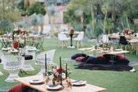 a boho wedding picnic in dark and jewel tones, with low hairpin tables, bright pillows, black candles and bright blooms