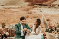 a boho wedding picnic with a printed blanket, a tray table, floral arrangements and dried florals, pampas grass