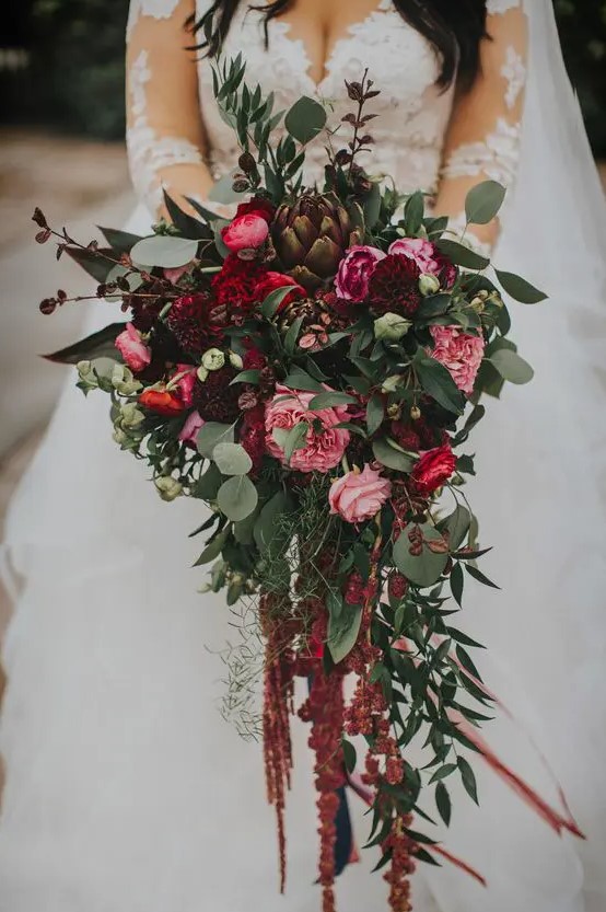 a bold exquisite cascading wedding bouquet of pink, burgundy blooms, greenery, dark foliage, artichokes and bulbs going down for a fall wedding