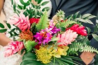 a bold tropical wedding bouquet composed of various tropical blooms including pincushion proteas and lots of leaves