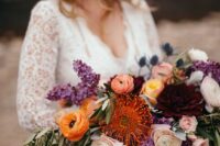 a bold wedding bouquet of blush and orange ranunculus, lilac, dramatic burgundy flowers and a pincushion protea