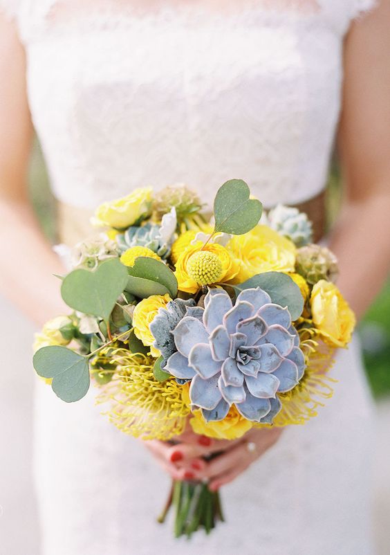 a bold wedding bouquet of yellow roses, billy balls, pincushion proteas, a succulent and greenery is a cool idea for a summer bride