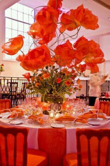 a bold wedding reception tablescape with red linens, bold red and orange blooms and matching oversized red flowers is wow