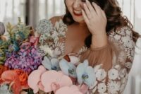 a bride rocking a fantastic iridescent statement wedding bouquet with colorful blooms, foliage and grasses for a wow factor