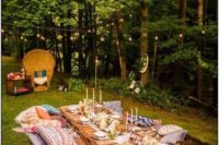 a bright boho summer wedding picnic with colorful rugs, pillows, a pallet table, thin candles and an airy runner