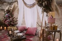 a bright desert boho picnic with a neutral backdrop with pompoms, colorful pillows, lots of candles, pampas grass and blooms