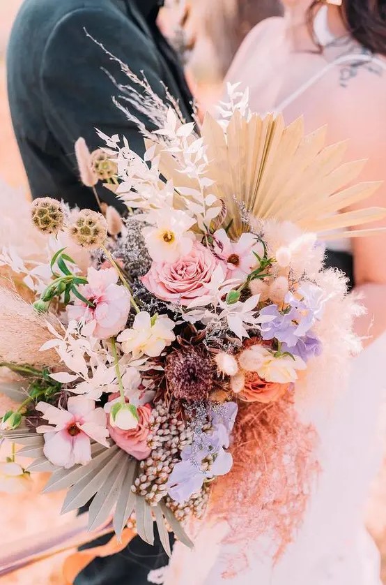 a bright iridescent wedding wedding bouquet of pink, neutral and lilac blooms, dried foliage, seed pods and fronds is wow