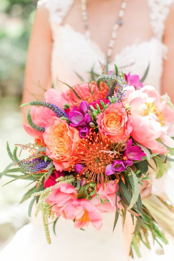 a bright wedding boquuet of pink peonies, roses, hot pink blooms and astilbe, pincushion proteas