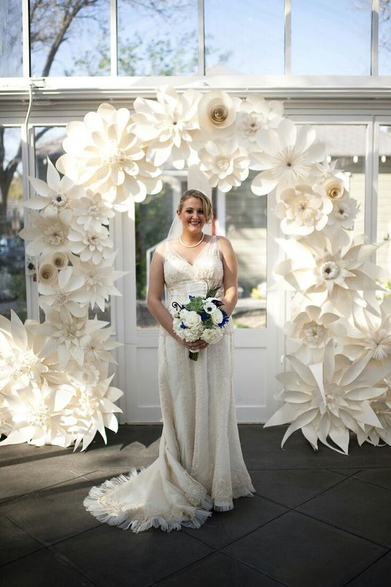 a catchy wedding arch made of white oversized paper blooms is a cool idea for an eco conscious wedding
