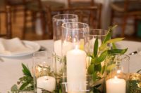 a chic and simple barn wedding centerpiece of foliage, candles in tall glasses and mercury glass candleholders