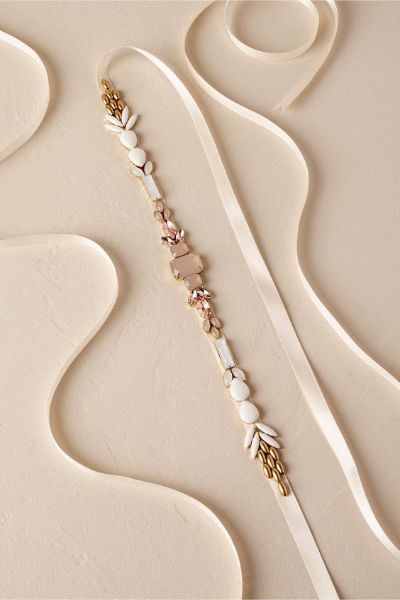 a chic neutral bridal sash with blush crystals and gold and white beads is a cool and refined idea for a modern bride
