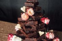 a chocolate brownie tower wedding cake topped with white and pink roses is a lovely and informal alternative to a usual wedding cake