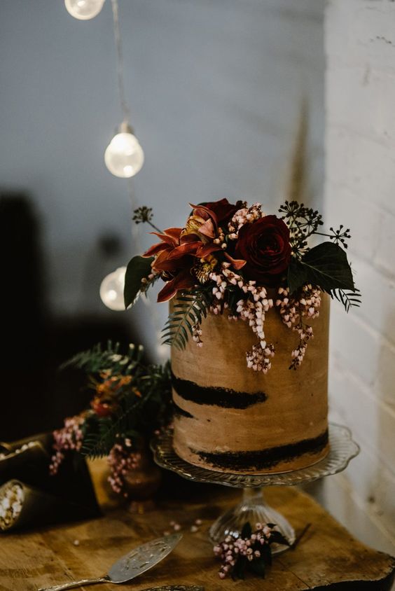 a chocolate naked wedding cake topped with pastel and deep colored blooms and greenery is a gorgeous idea for a wedding