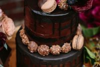 a chocolate wedding cake with chocolate drip, chocolate and macarons, deep-colored blooms on top for a jewel-tone fall wedding