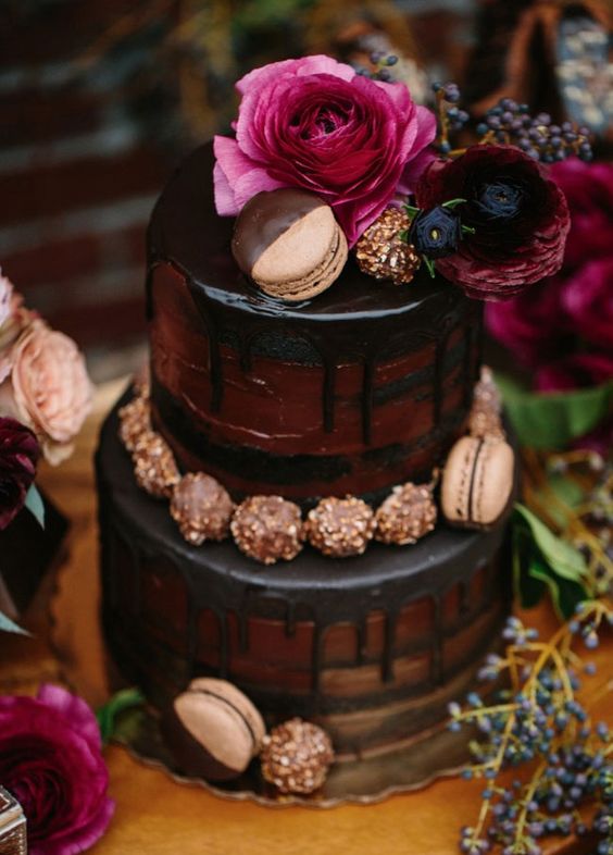 a chocolate wedding cake with chocolate drip, chocolate and macarons, deep-colored blooms on top for a jewel-tone fall wedding