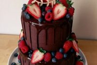 a chocolate wedding cake with chocolate drip, fresh berries and a calligraphy cake topper is a fantastic and delicious-looking idea for a wedding