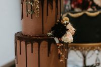 a chocolate wedding cake with chocolate drip, with dark and pastel blooms, berries and greenery is a refined and yummy wedding dessert idea