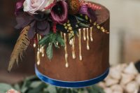 a chocolate wedding cake with gold drip, pastel and dark blooms, feathers and greenery is an amazing idea for a boho wedding