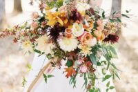 a colorful and dimensional fall bouquet with yellow, pink, white, red flowers and greenery and red leaves plus a cascade for a catchier look