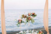 a colorful beach bridal shower picnic setting with bold blooms and textiles, colorful glasses, candleholders