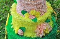 a colorful cake-shaped pinata wedding guest book topped and decorated with bright paper blooms and leaves is a very fun and bright idea