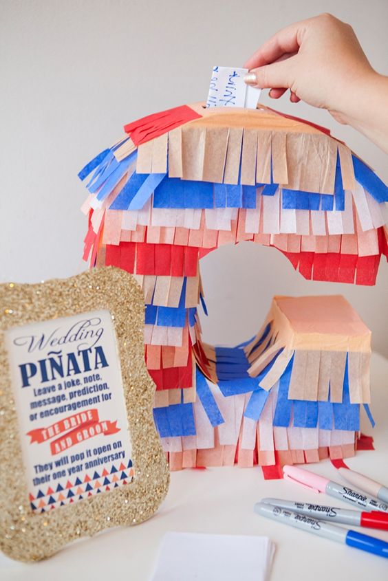 a colorful monogram pinata wedding guest book with fringe is a very cool and fun idea for a modern romantic wedding