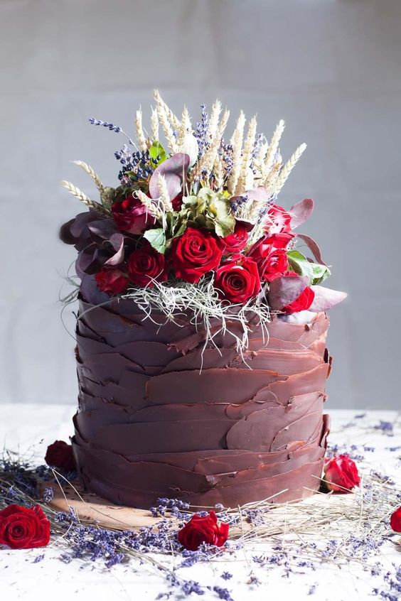 a creative chocolate tier wedding cake topped with lavender, wheat, red and burgundy blooms and greenery is amazing for a fall wedding