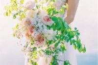 a creative textural wedding bouquet with bold greenery and some blush peonies for a delicate spring bridal look