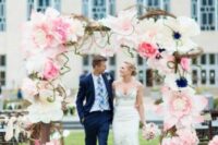 a creative wedding arch decorated with pink and white oversized blooms and twigs is a cool and chic idea for a wedding