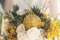 a creative wedding bouquet with white and yellow blooms, mimosa, billy balls and various types of greenery