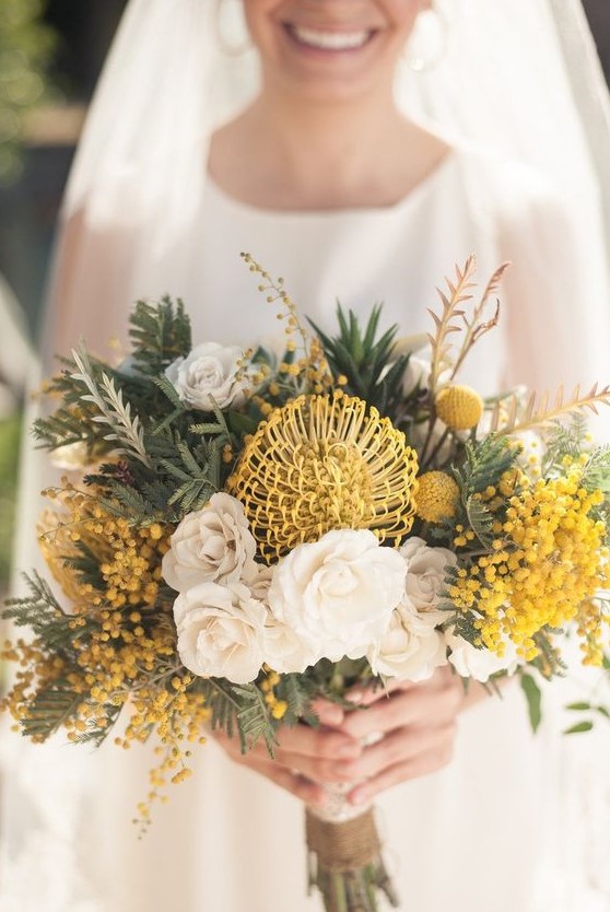 a creative wedding bouquet with white and yellow blooms, mimosa, billy balls and various types of greenery