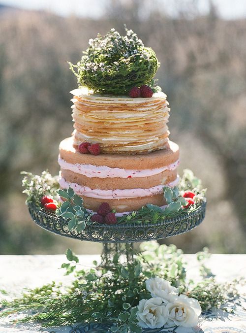 a creative wedding cake with a crepe tier and a naked tier, with strawberry cream, greenery and berries is wow