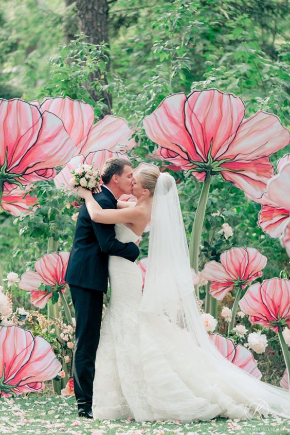 a creative wedding ceremony space done with oversized pink blooms and usual pink flowers is a stylish and bold idea for a modern wedding