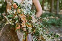 a fab oversized wedding bouquet of peachy and rust-colored blooms, greenery, white fillers and various foliage for the fall
